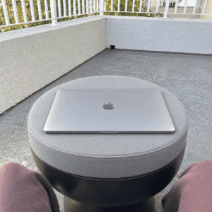 Firm foam laptop riser cushion serving as a couch laptop desk, used on an apartment balcony