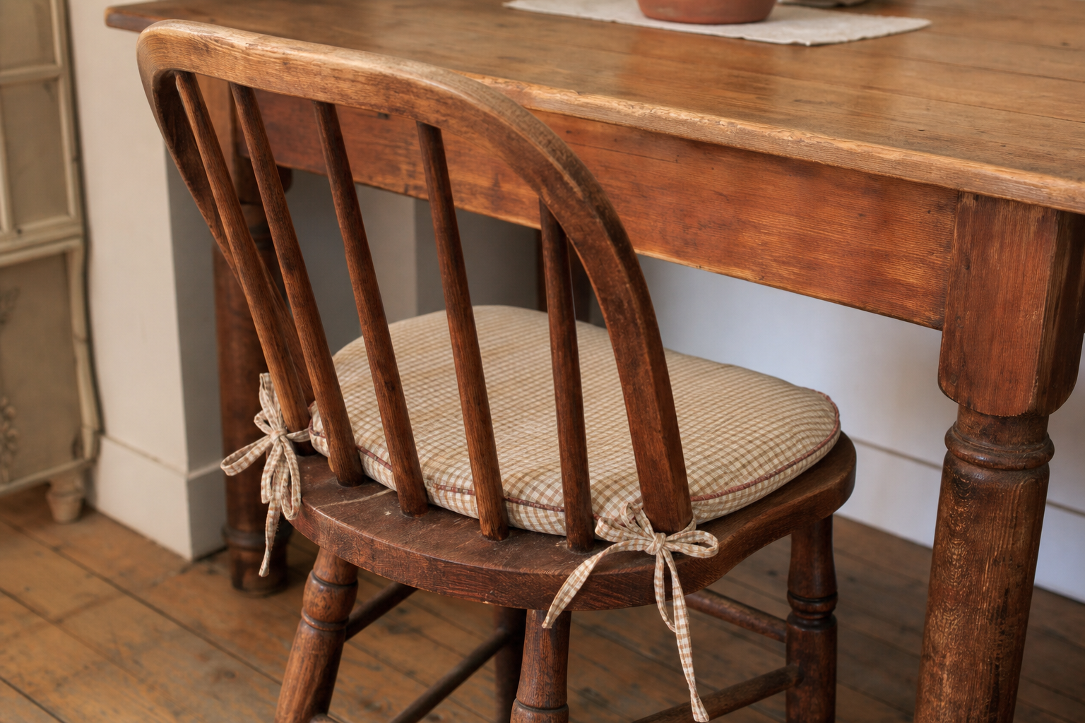 Vintage wooden spindle back chair with a gingham tie-on seat cushion under a farmhouse table - one of the open-back wood chair family that ladder backs belong to