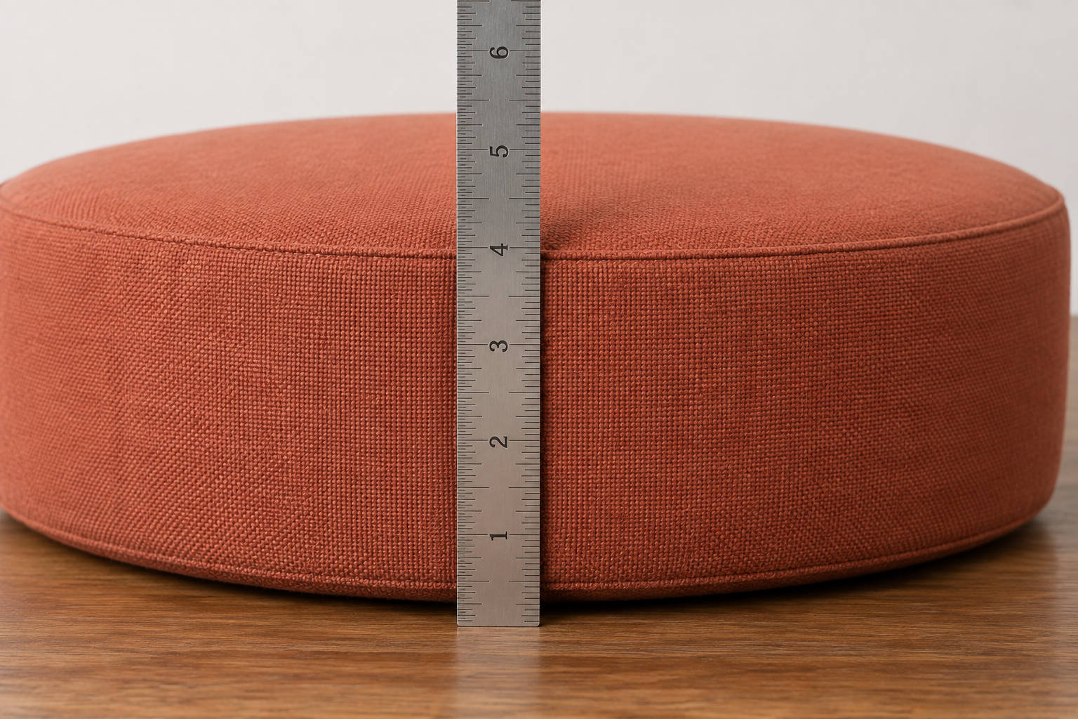 Measuring cushion thickness at the seam with a steel rule — thickness is read unsqueezed