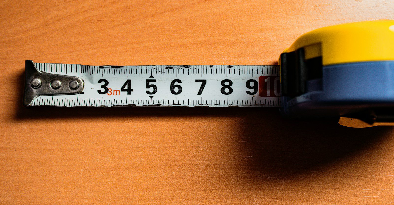 A well-used tape measure on a wooden workbench - measure the old foam core before ordering new chair cushions