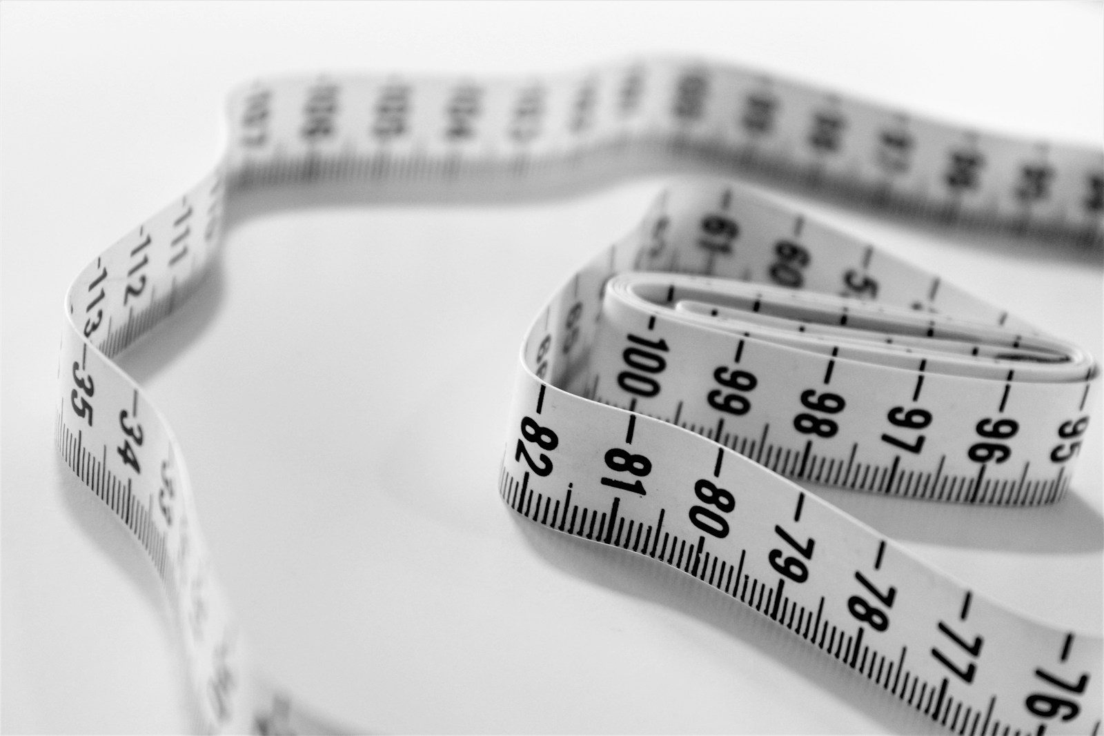 Soft measuring tape coiled on a white surface - ordering upholstery foam starts with seam-to-seam measurements in inches
