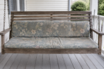Worn-out faded flattened porch swing cushions sagging on the slats - the old pads that need replacing