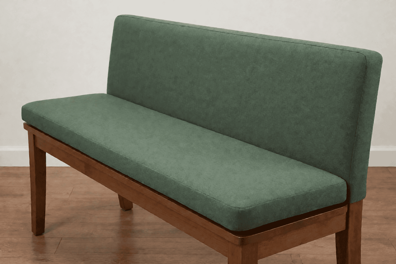 Low side-angle view along a dining bench showing the substantial thickness of its deep sage green cushion pad rising above the wooden seat board
